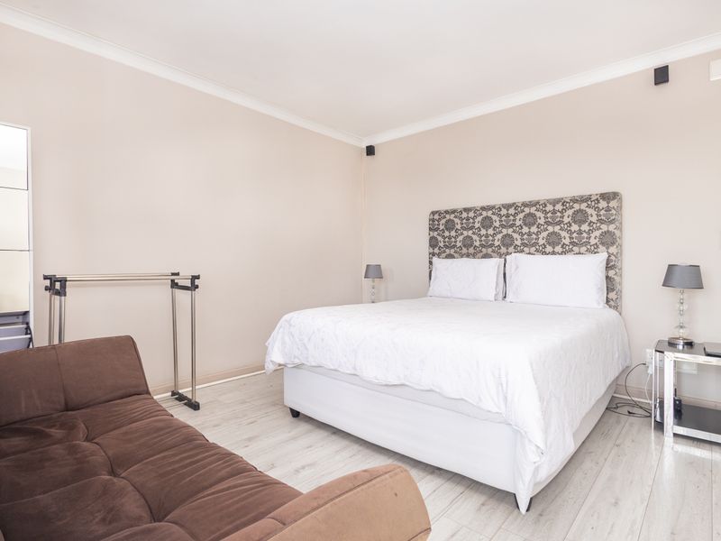 A well-maintained bedroom featuring light-toned laminate flooring, neutral wall finishes, and decorative coving, providing a clean and comfortable living space.