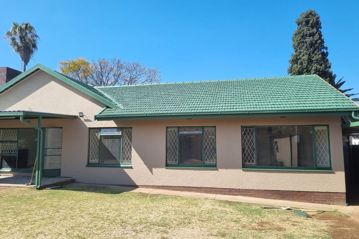 Rear view of the house featuring a tiled roof, leaded glass windows, and a covered patio area overlooking the garden.