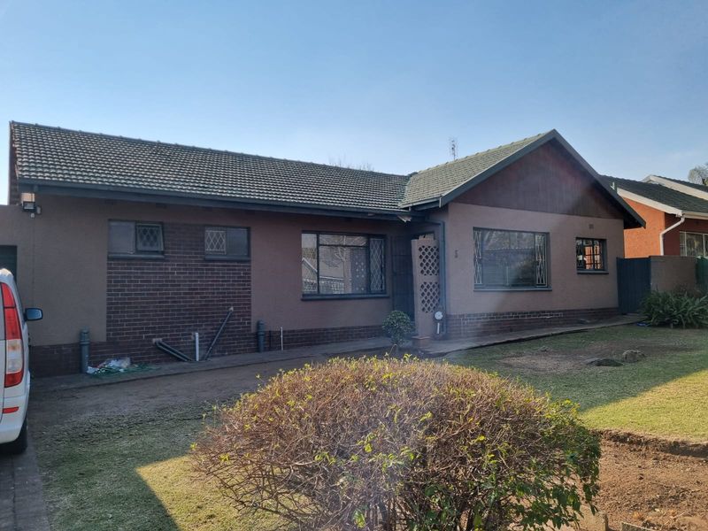 Front elevation of a single-story house featuring a tiled roof, brick and rendered facade, and security bars on windows.
