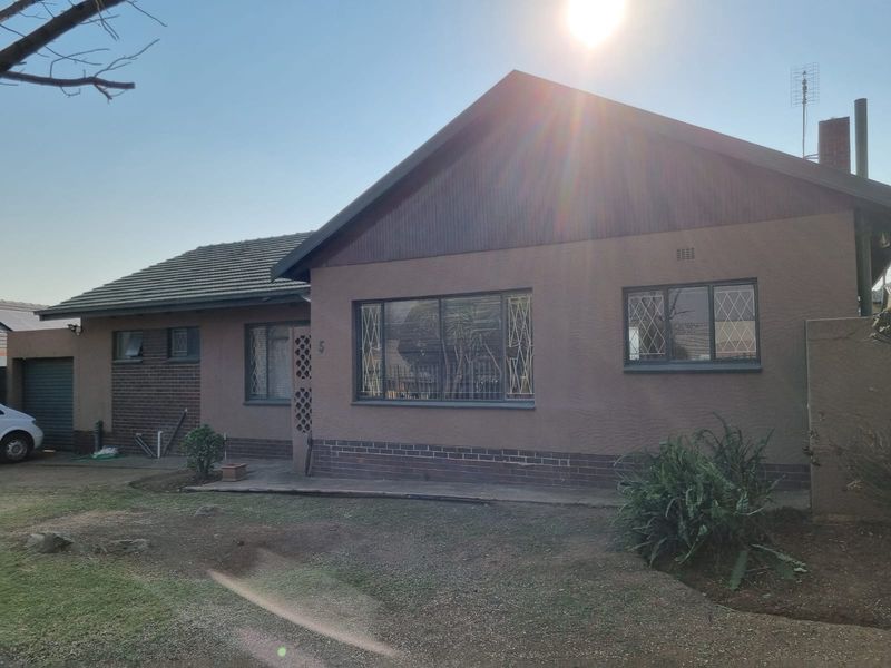 Front elevation of a single-story house featuring a tiled roof, brick and plaster facade, and an attached garage.