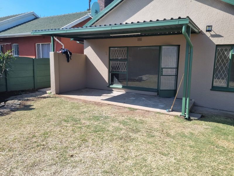 A covered outdoor patio area featuring paved flooring, security gates, and direct access to the garden, providing a functional space for outdoor relaxation.