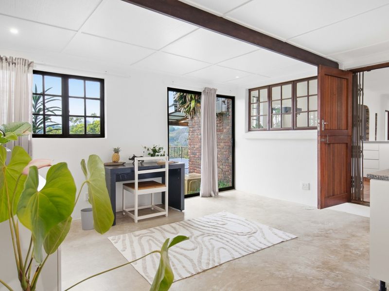 Bright living area featuring exposed ceiling beams, polished tiled flooring, and direct access to the outdoor space through a sliding glass door.