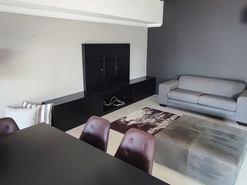 A contemporary living room featuring a built-in media console and light-toned laminate flooring, offering a clean and functional space.