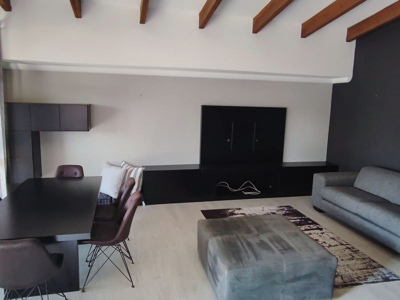 Spacious open-plan living and dining area featuring exposed timber ceiling beams, modern laminate flooring, and integrated built-in media cabinetry.