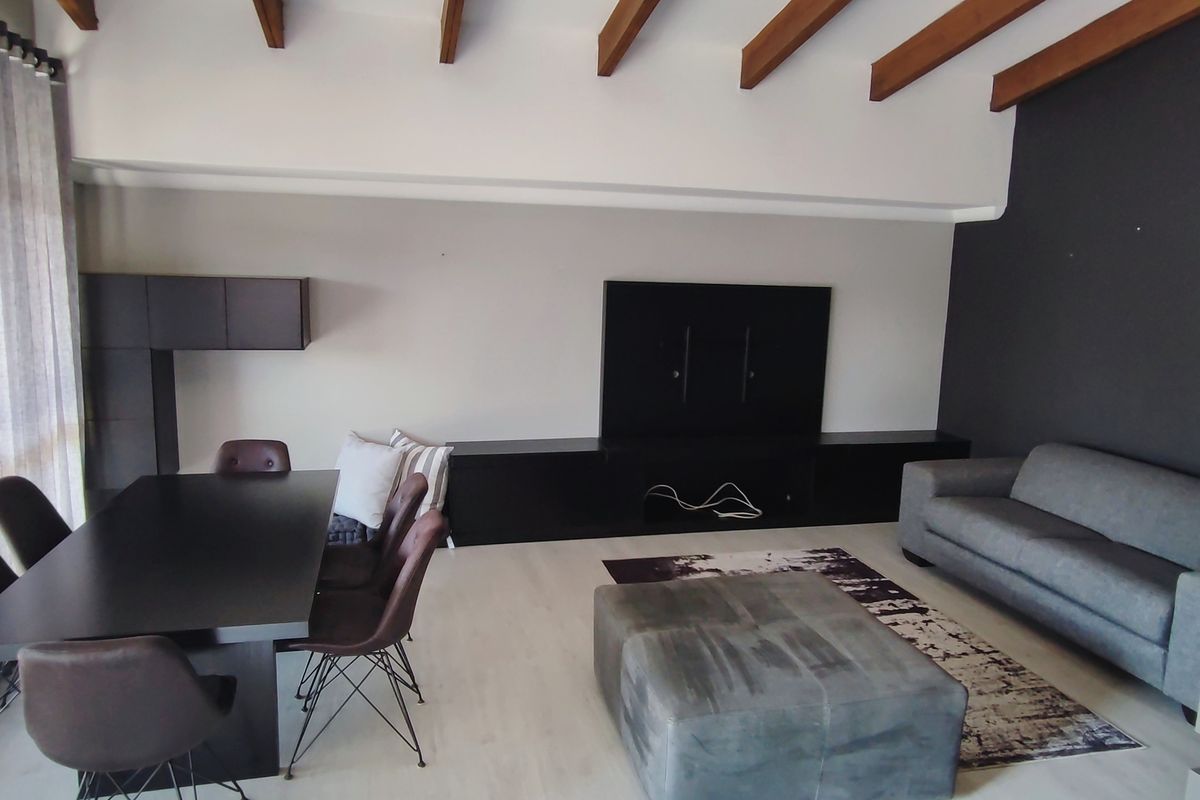 Spacious open-plan living and dining area featuring exposed timber ceiling beams, modern laminate flooring, and integrated built-in media cabinetry.