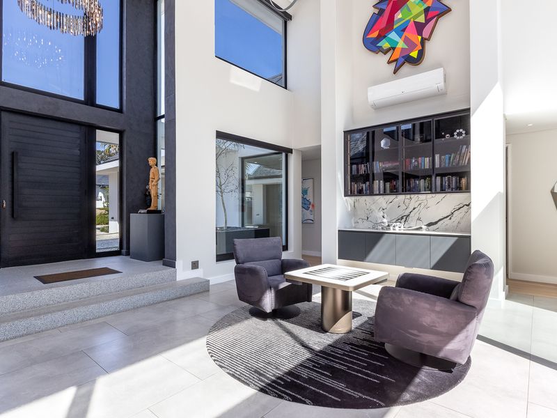 Spacious double-volume entrance hall featuring large format floor tiles, built-in cabinetry with marble detailing, and abundant natural light through expansive windows.