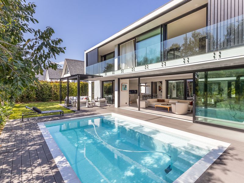 Modern outdoor living space featuring a swimming pool, composite decking, and seamless indoor-outdoor flow through large sliding glass doors to the main living area.