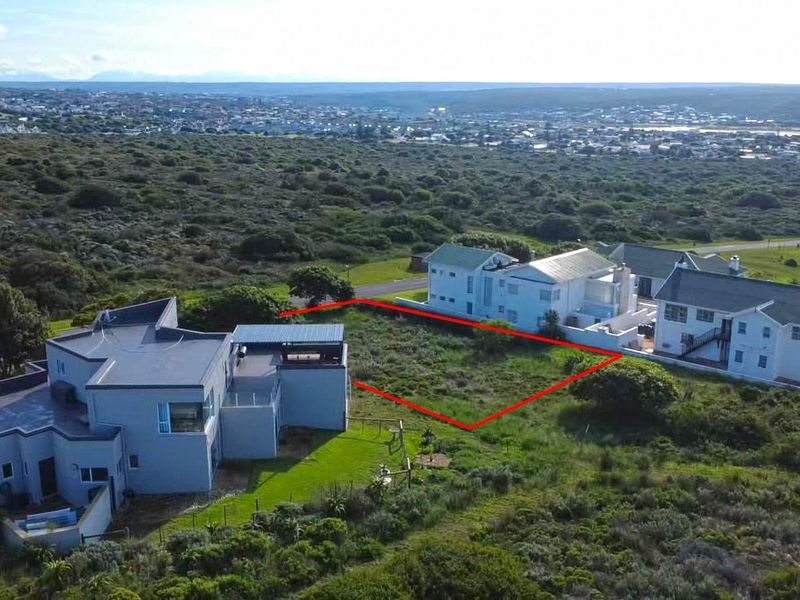 Aerial view of a vacant residential plot situated in a coastal neighborhood, highlighting the available land area and surrounding environment.