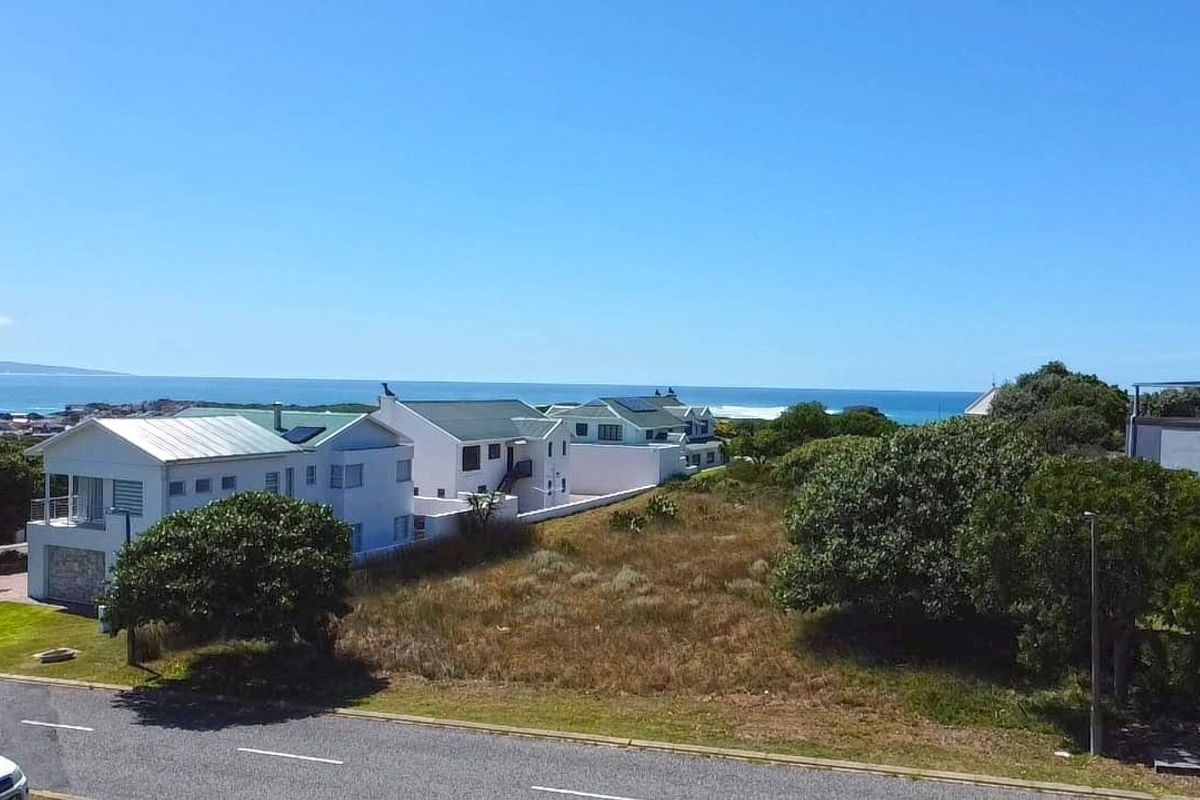 An aerial view of a vacant residential plot situated in a coastal neighborhood with ocean views.