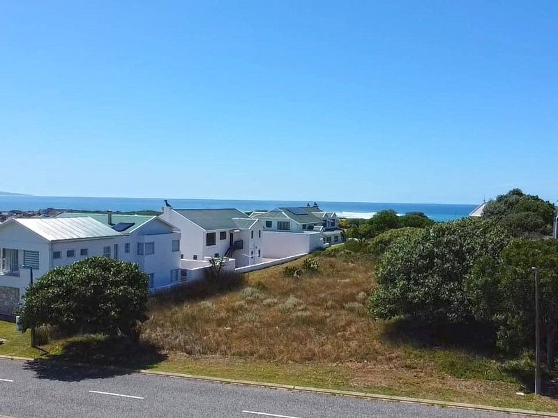 An aerial view of a vacant residential plot situated in a coastal neighborhood with ocean views.