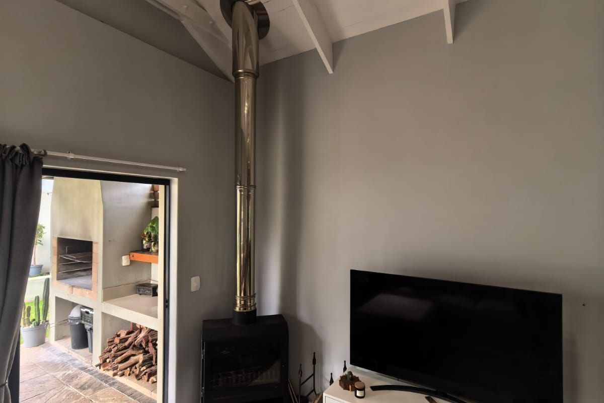 Living room featuring a freestanding fireplace, exposed rafters, and tiled flooring, with direct access to an outdoor patio area.