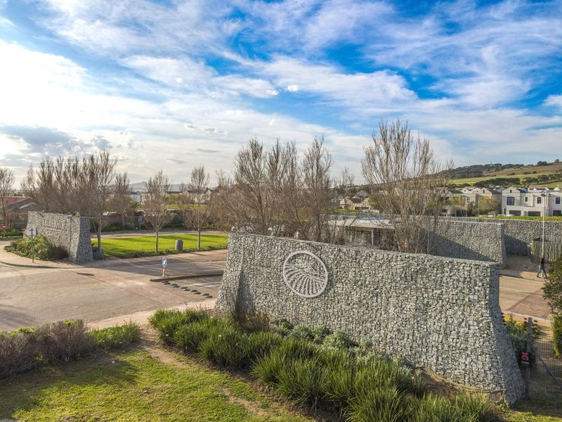 An aerial view of the Kelderhof Country Estate entrance, featuring prominent gabion stone boundary walls, paved access roads, and manicured landscaping.