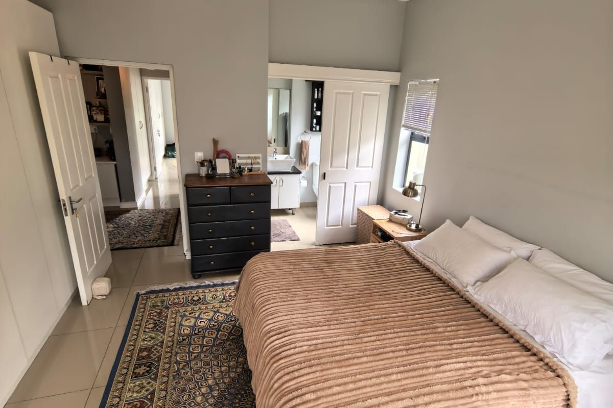 A well-maintained bedroom featuring tiled flooring, built-in cupboards, and direct access to an en-suite bathroom.
