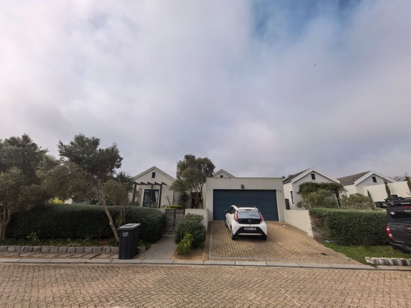 Front elevation of a modern residential property featuring a paved driveway, double garage, and established garden hedging.
