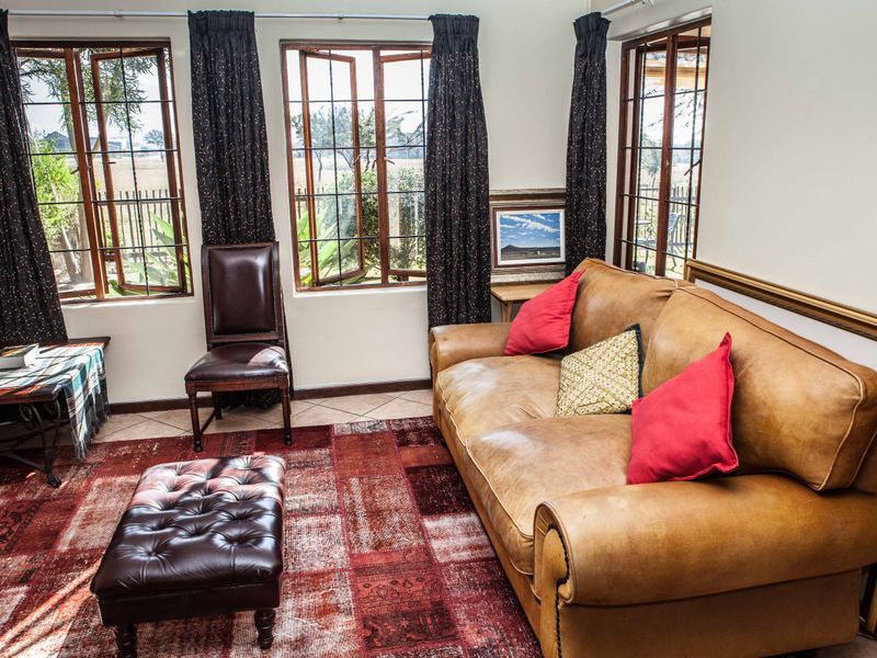 A comfortable living room featuring tiled flooring and multiple casement windows that provide natural light and views of the exterior.