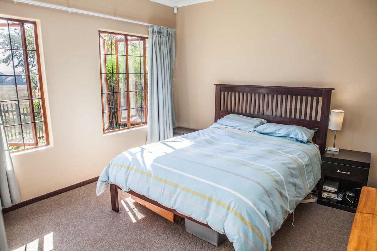 A well-lit bedroom featuring carpeted flooring and dual casement windows, providing a comfortable and functional living space.