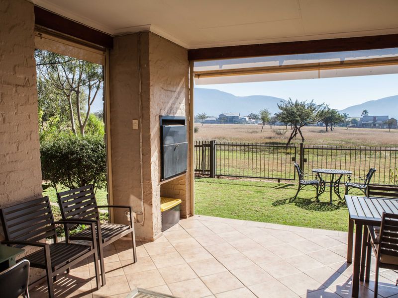 Covered patio featuring a built-in braai, tiled flooring, and direct access to a private garden with scenic mountain views.