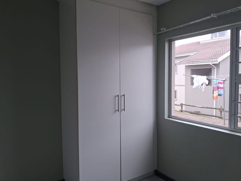 A clean, empty bedroom featuring a white built-in wardrobe and a window with security bars, offering a neutral space ready for personalization.