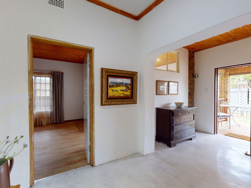Entrance hall featuring polished concrete floors, exposed brick accents, and timber ceiling details, providing access to adjacent living spaces and an outdoor patio area.