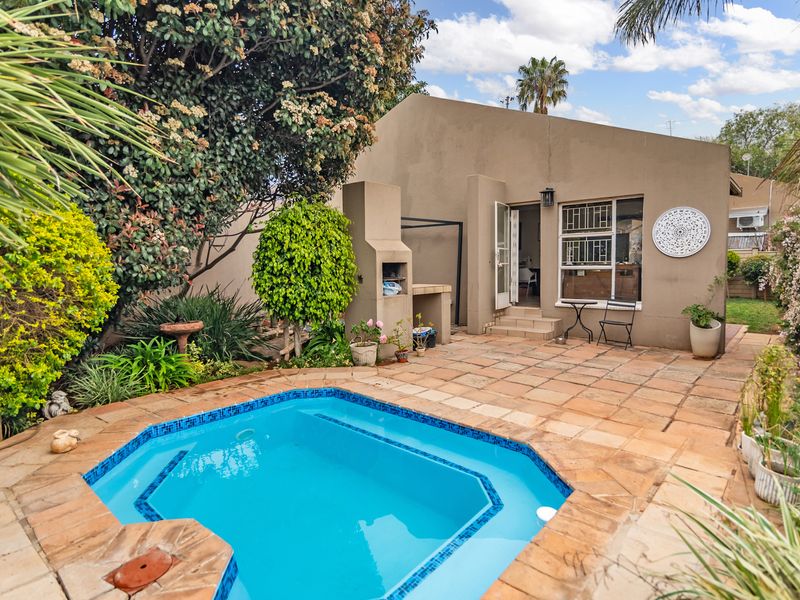 Outdoor entertainment area featuring a swimming pool, paved patio, and a built-in braai, providing a functional space for relaxation and social gatherings.