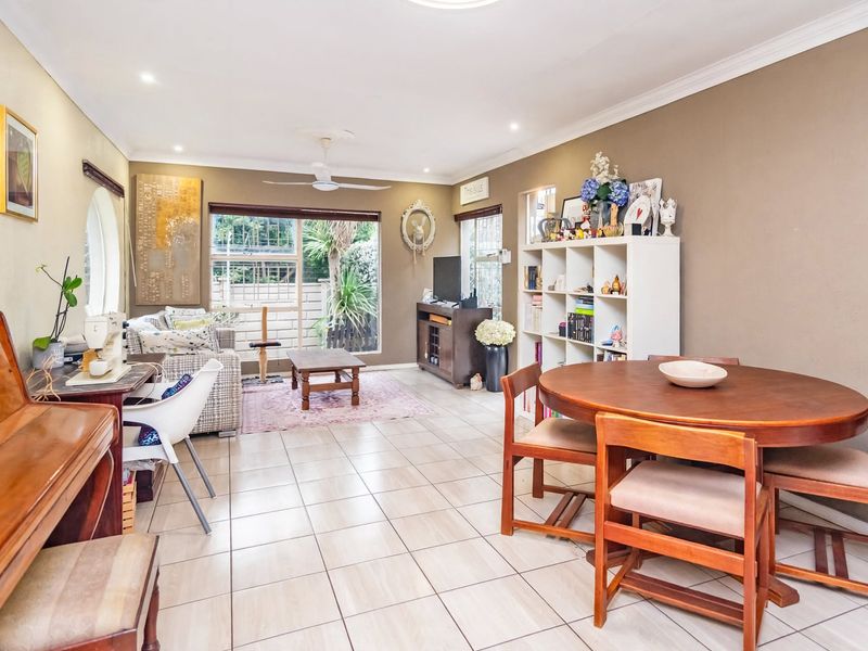 Spacious open-plan living and dining area featuring neutral tiled flooring, recessed lighting, a ceiling fan, and large sliding doors leading to the garden.