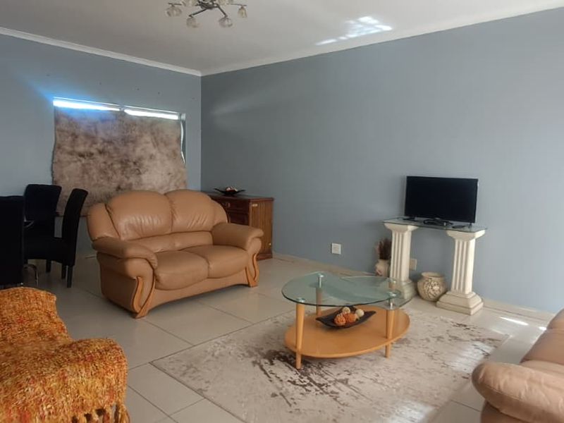 A spacious living room featuring neutral tiled flooring and light-toned walls, providing a functional and versatile area for relaxation.