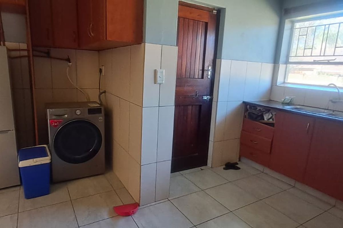A functional kitchen space featuring tiled flooring, built-in cabinetry, and a stainless steel sink, requiring some cosmetic updates and repairs to cabinetry.