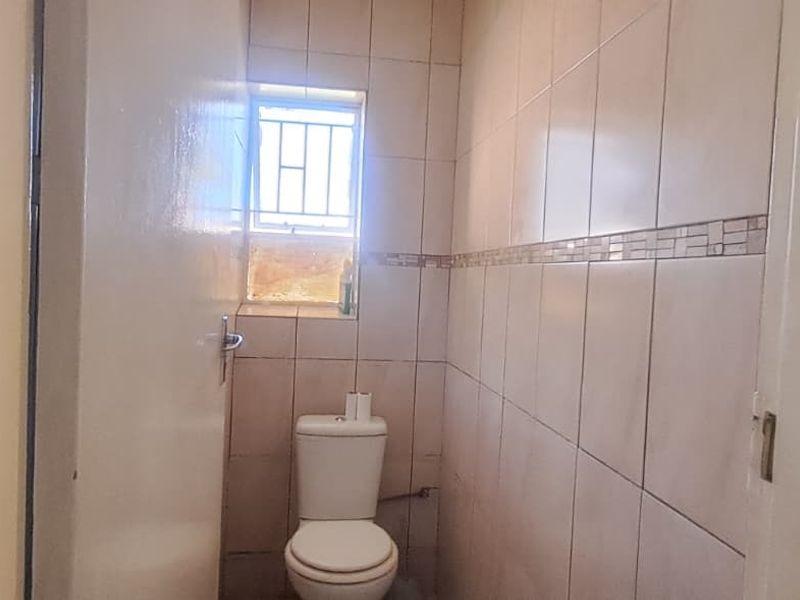 A compact guest bathroom featuring tiled walls and a standard toilet, requiring minor cosmetic updates to improve its overall appearance.