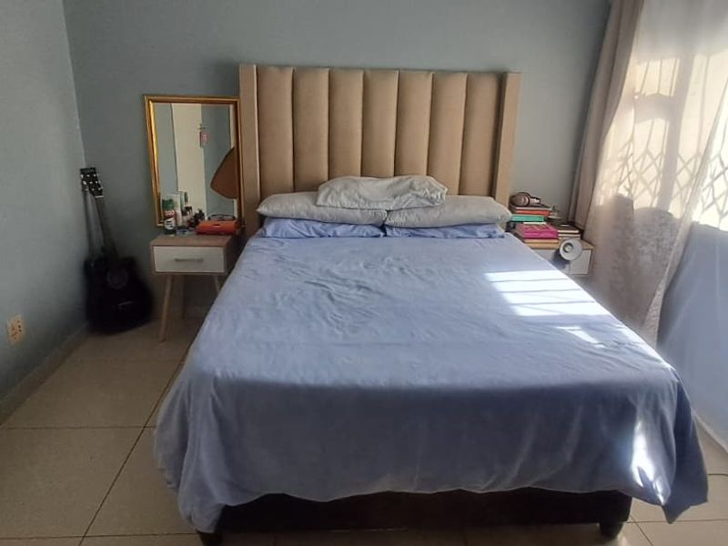 A functional bedroom featuring tiled flooring and a window fitted with a security gate.