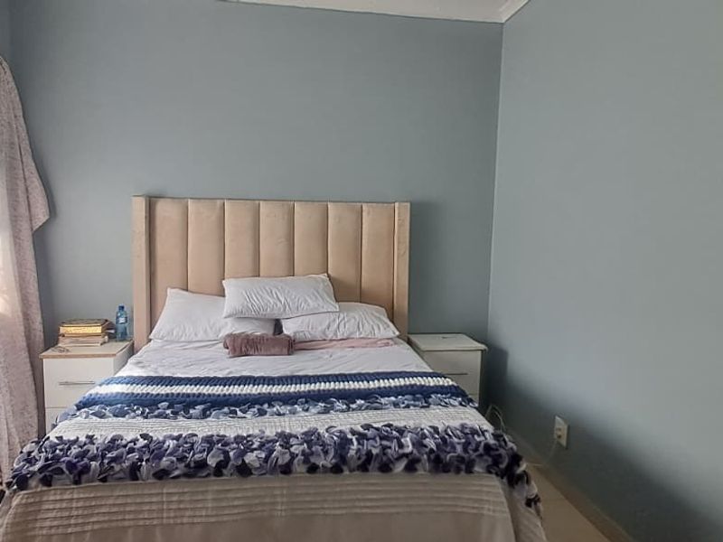 A bedroom featuring blue painted walls, a window with a security gate, and neutral flooring.