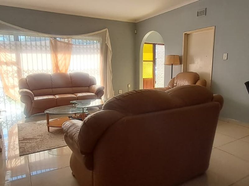 A spacious living room featuring tiled flooring and an arched entryway, providing a functional layout with natural light from the large window.
