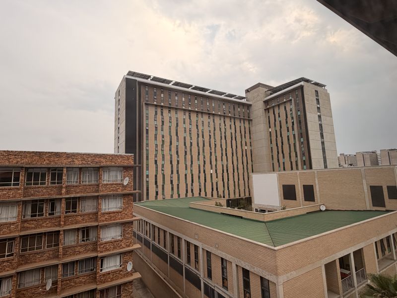 An elevated urban view showcasing surrounding multi-story apartment buildings with brick facades and metal roofing in a dense residential area.