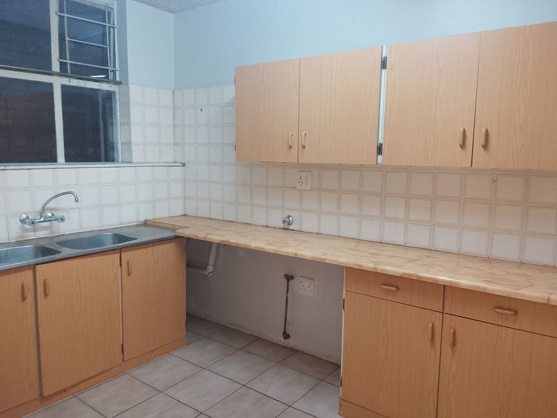 A functional kitchen featuring laminate countertops, double bowl sink, tiled backsplash, and ample built-in wooden cabinetry, ready for a modern update.