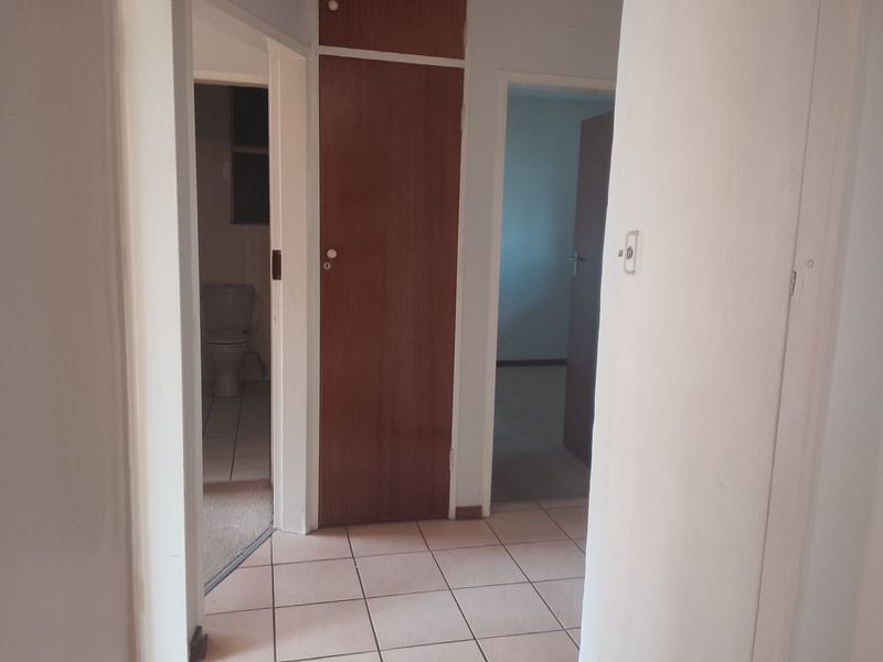 A functional hallway featuring tiled flooring and built-in storage cupboards, providing access to adjacent rooms within the apartment.