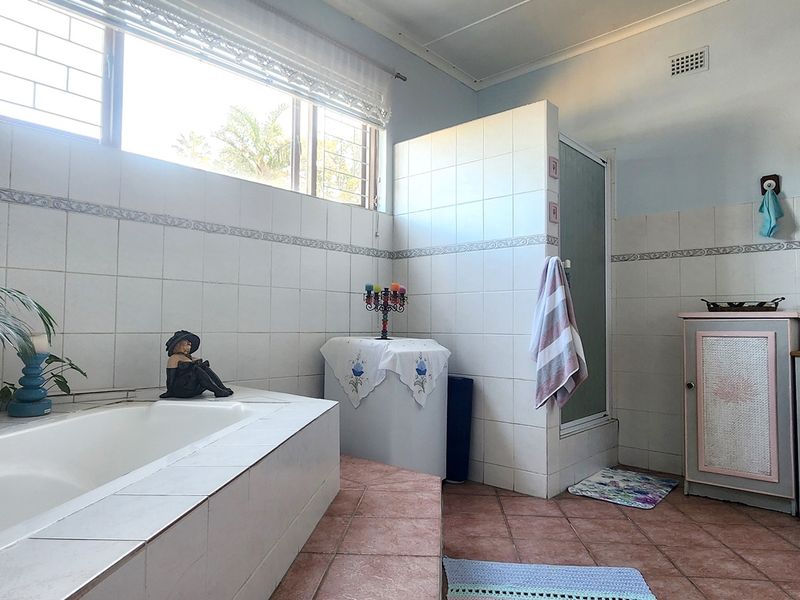 Spacious bathroom featuring a built-in bathtub, separate tiled shower enclosure, and vanity cabinet with integrated storage.