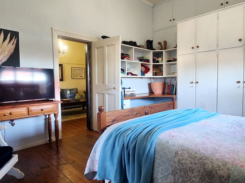 A bedroom featuring hardwood flooring, extensive built-in cabinetry with overhead storage, and a built-in corner desk unit.