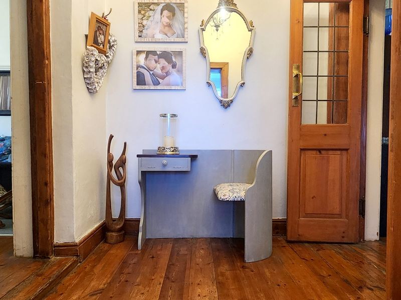 A traditional hallway featuring warm timber flooring, classic leaded glass timber doors, and original architectural character.