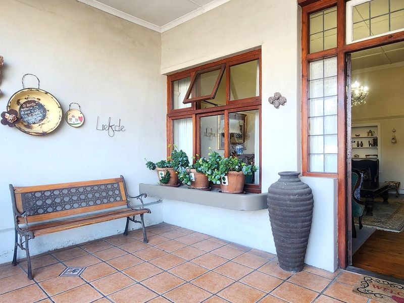 A covered patio area featuring tiled flooring, timber-framed windows with leaded glass details, and direct access into the home's interior.