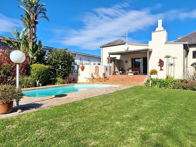 Rear exterior view featuring a swimming pool, brick patio area, and well-maintained lawn, providing a private outdoor entertainment space.