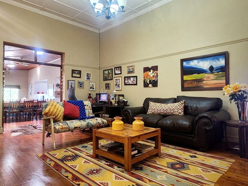 Spacious living room featuring original hardwood flooring and a classic pressed metal ceiling, offering a warm and character-filled atmosphere.