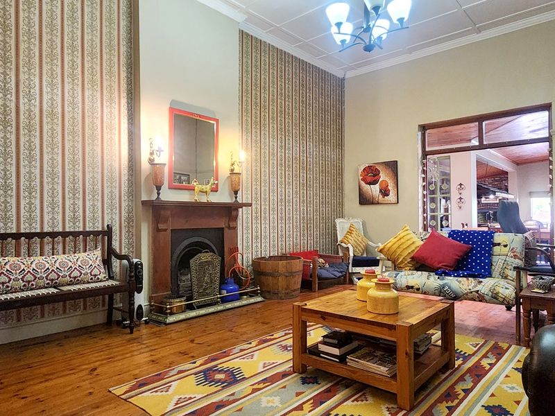 A character-filled living room featuring original timber flooring, a traditional fireplace, and decorative wallpaper, offering a warm and inviting atmosphere.