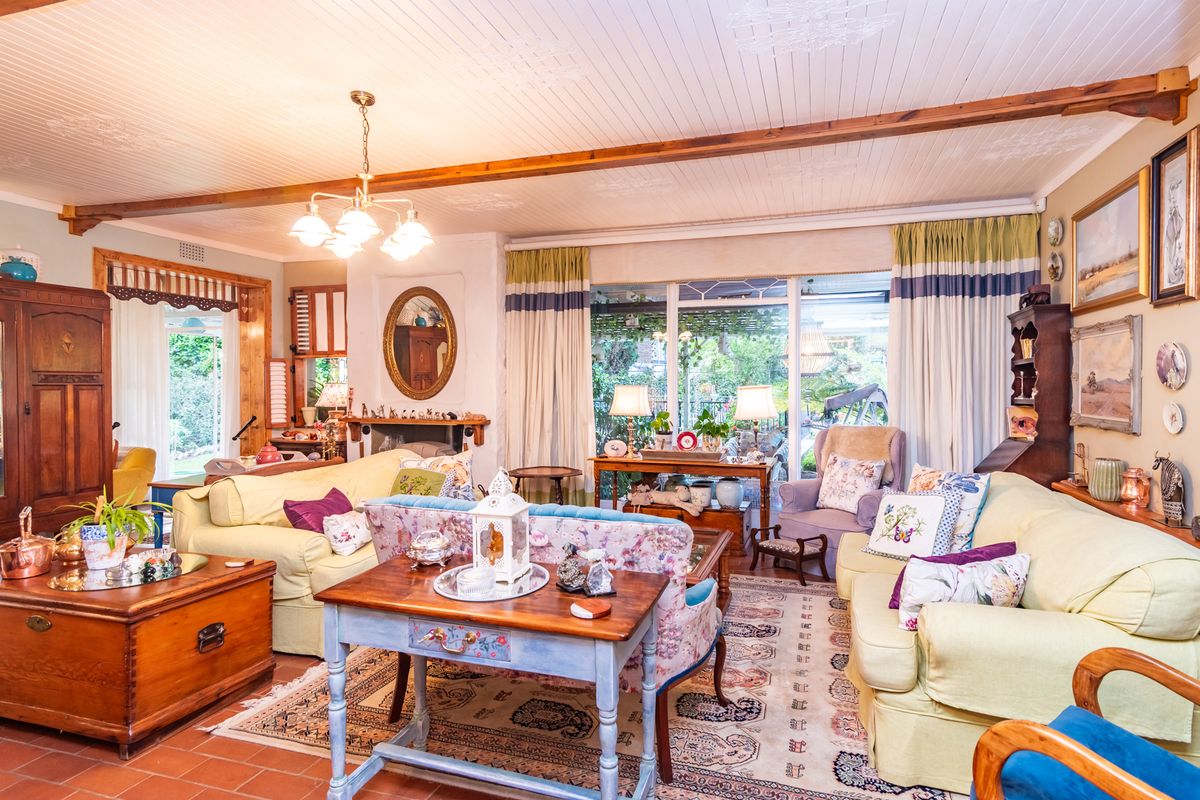 Spacious living room featuring exposed timber ceiling beams, terracotta flooring, a fireplace, and large sliding glass doors providing access to the garden.