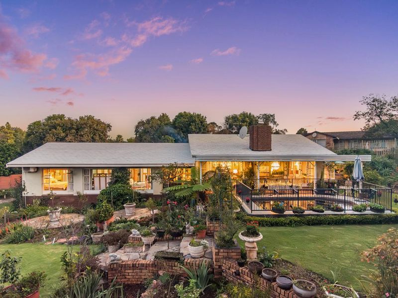 Rear view of the residence featuring a covered patio, swimming pool with safety fencing, and landscaped garden with brick retaining walls.