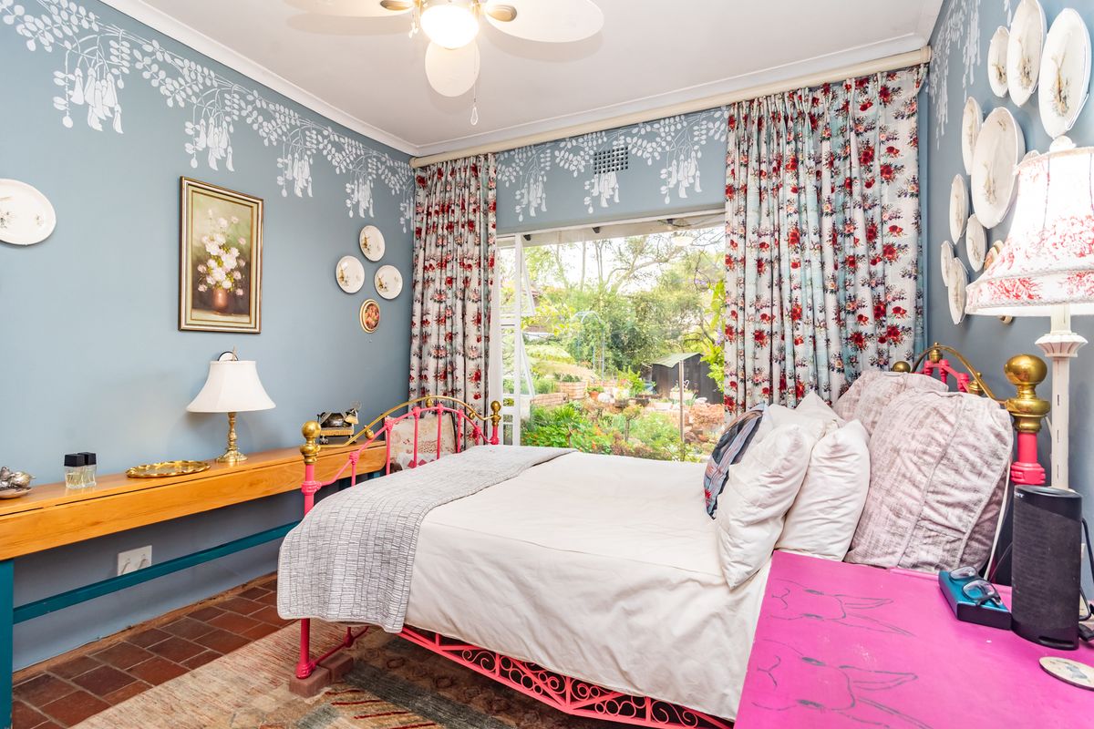 A bedroom featuring terracotta tile flooring, a ceiling fan, and a sliding glass door providing direct access to the garden.