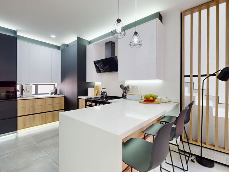 Modern kitchen featuring sleek two-tone cabinetry, stone countertops, a functional island, and integrated appliances with contemporary lighting and a timber slat feature screen.