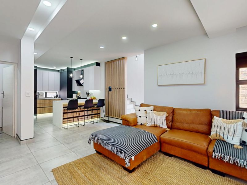 Modern open-plan living area featuring a sleek kitchen with island, recessed lighting, and contemporary timber slat detailing, seamlessly flowing into the lounge space.
