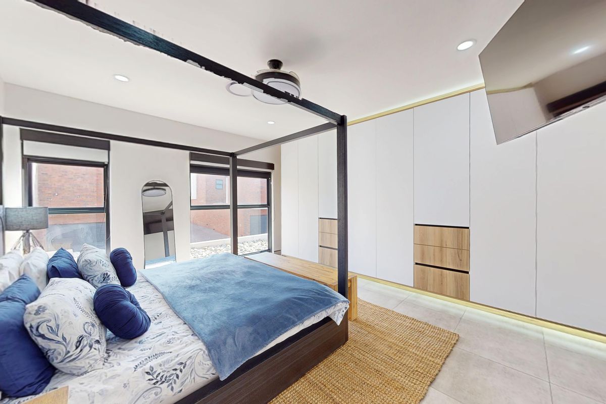 Modern bedroom featuring extensive built-in cabinetry with integrated lighting, tiled flooring, and large windows providing ample natural light.