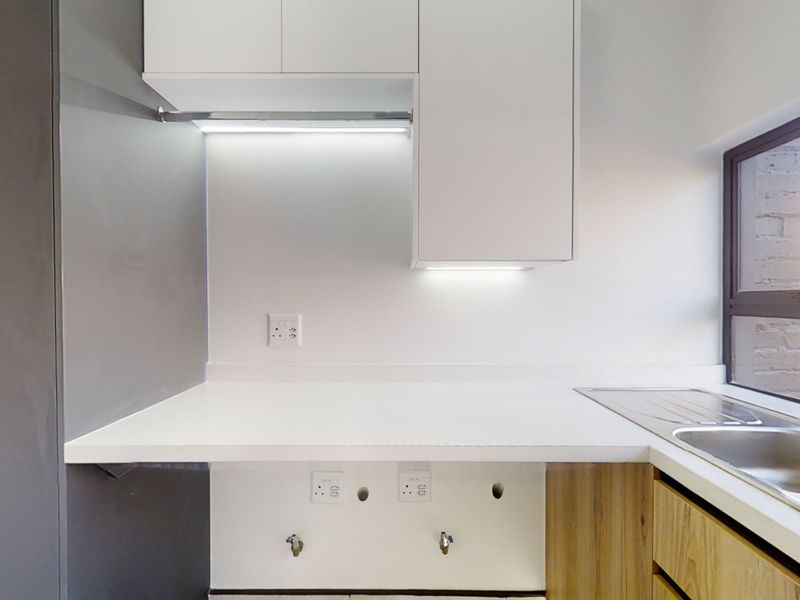 A clean, modern laundry area featuring built-in white cabinetry, a stainless steel sink, and dedicated plumbing connections for appliances.