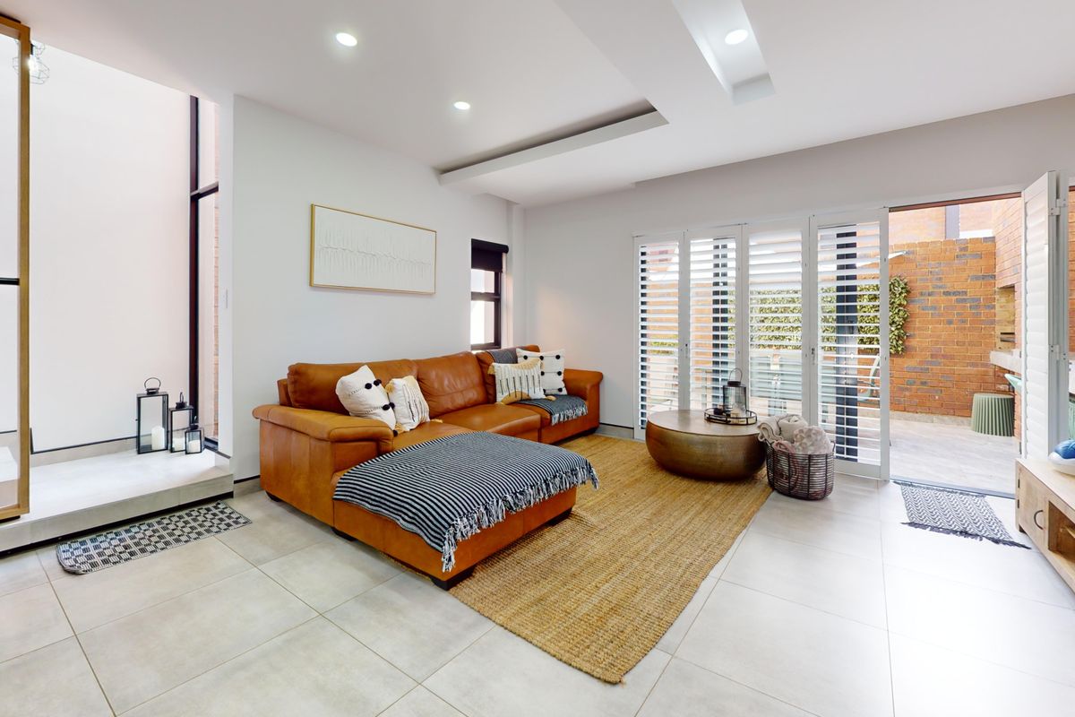 Modern living room featuring tiled floors, recessed lighting, and bi-fold doors opening to a private brick-walled courtyard.