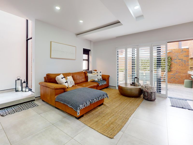Modern living room featuring tiled floors, recessed lighting, and bi-fold doors opening to a private brick-walled courtyard.